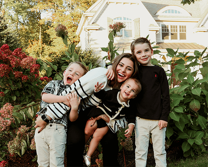 au pair with host children in front of flowers