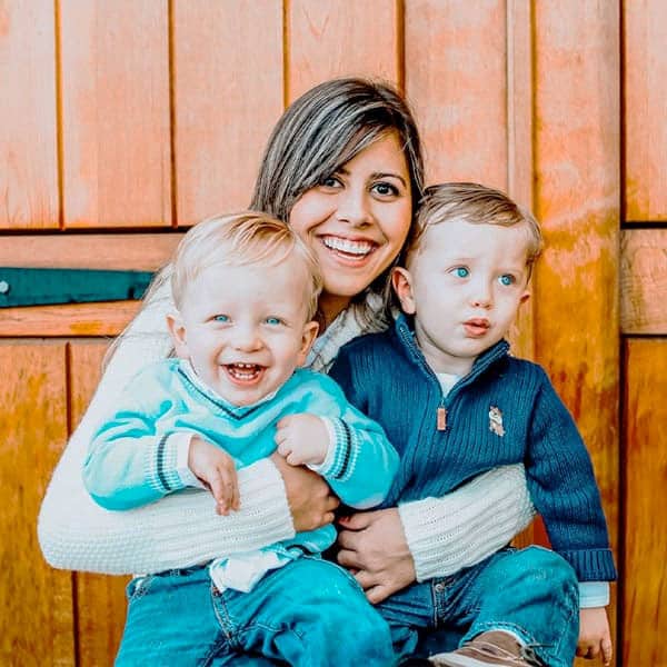 An au pair holding two toddler boys.