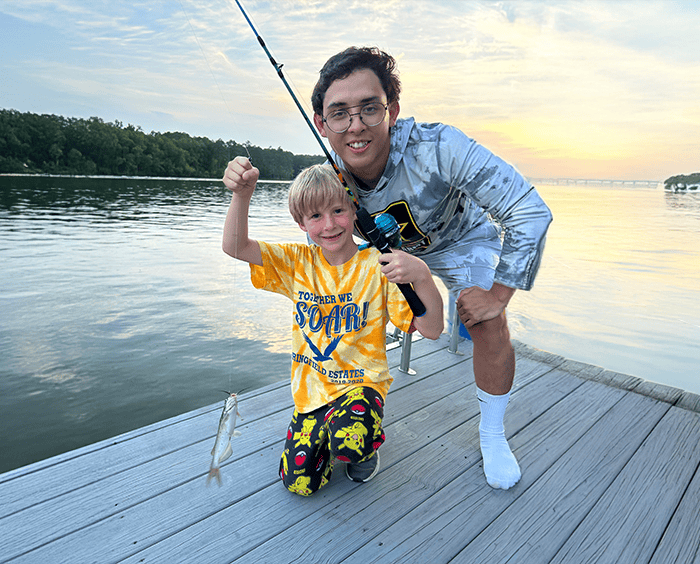 male au pair fishing with child.