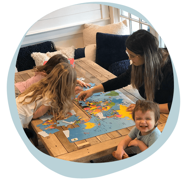 au pair doing puzzle with children.