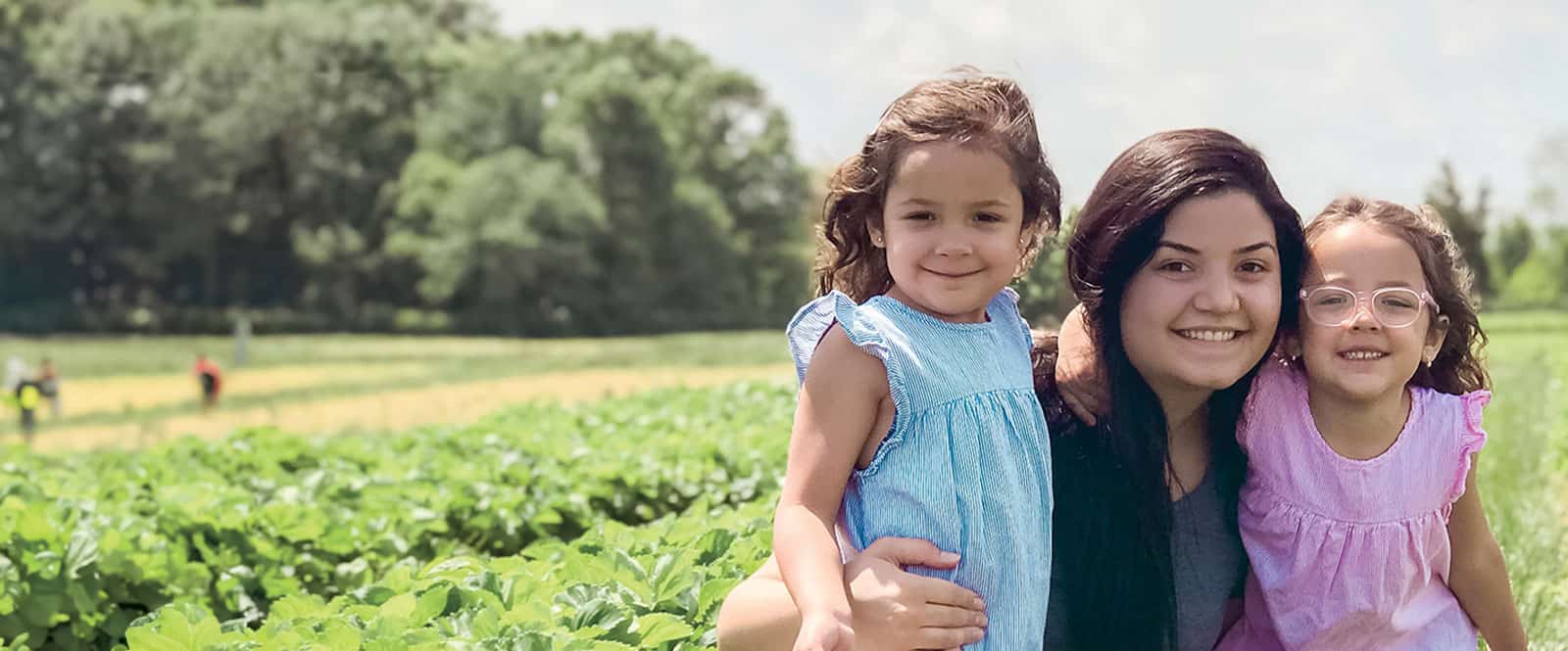Au pair with two children in a field.