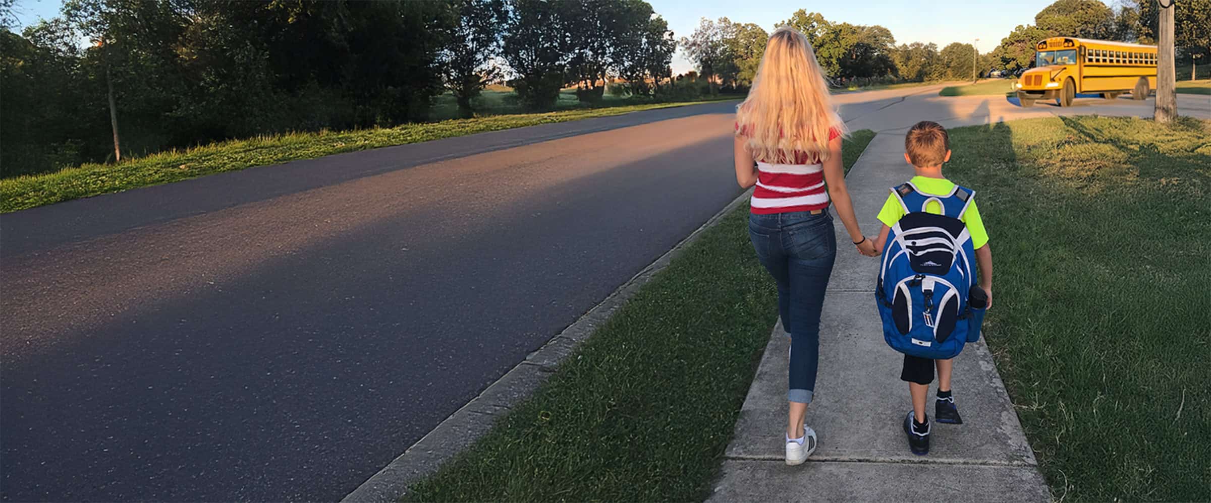 au pair walking child to bus.